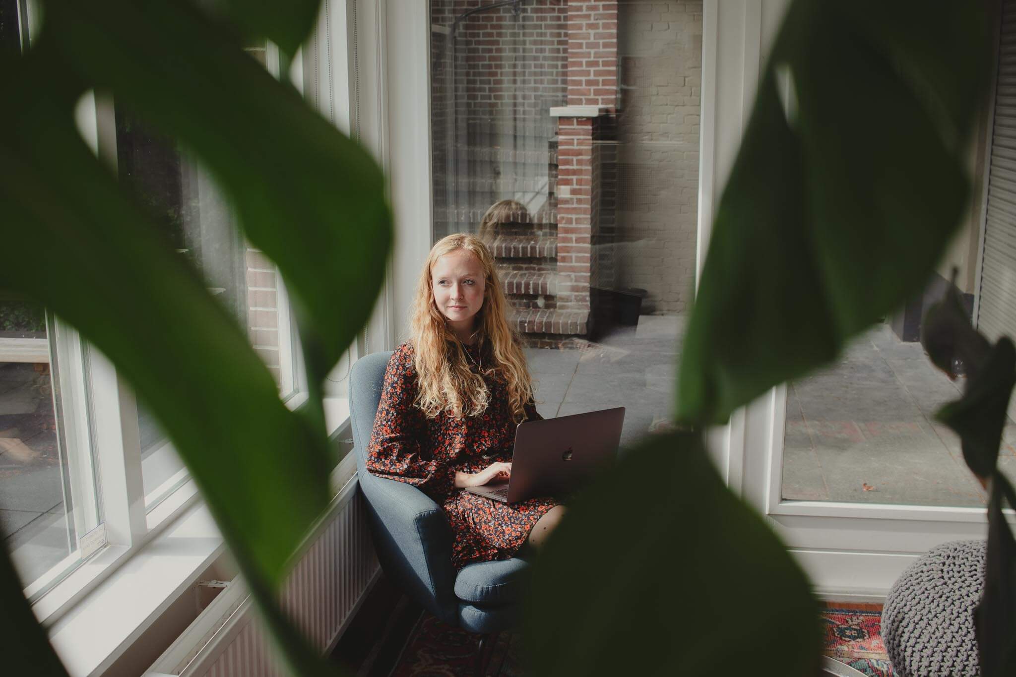 ZZP'er kijkt nadenkend uit het raam tijdens haar werkzaamheden